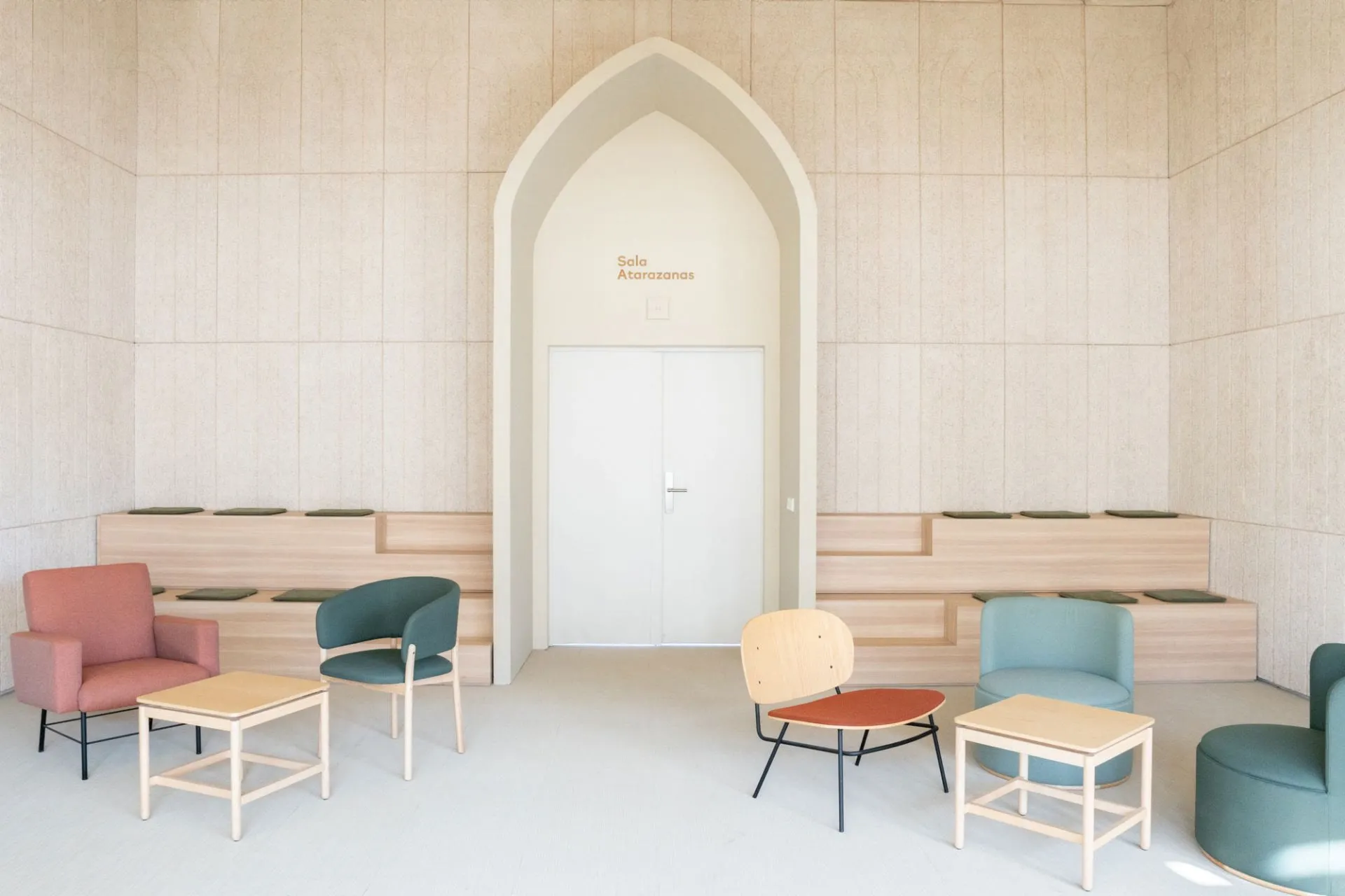 Atarazanas con sillones de colores, mesas bajas y paneles de madera en torno a un arco