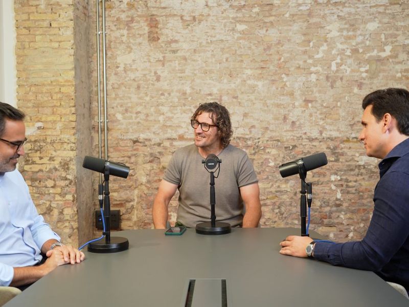 Tres personas grabando alrededor de una mesa con micrófonos